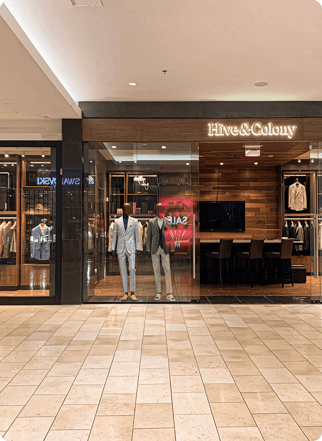 Hive & Colony storefront with mannequins and tailored suits in a mall.