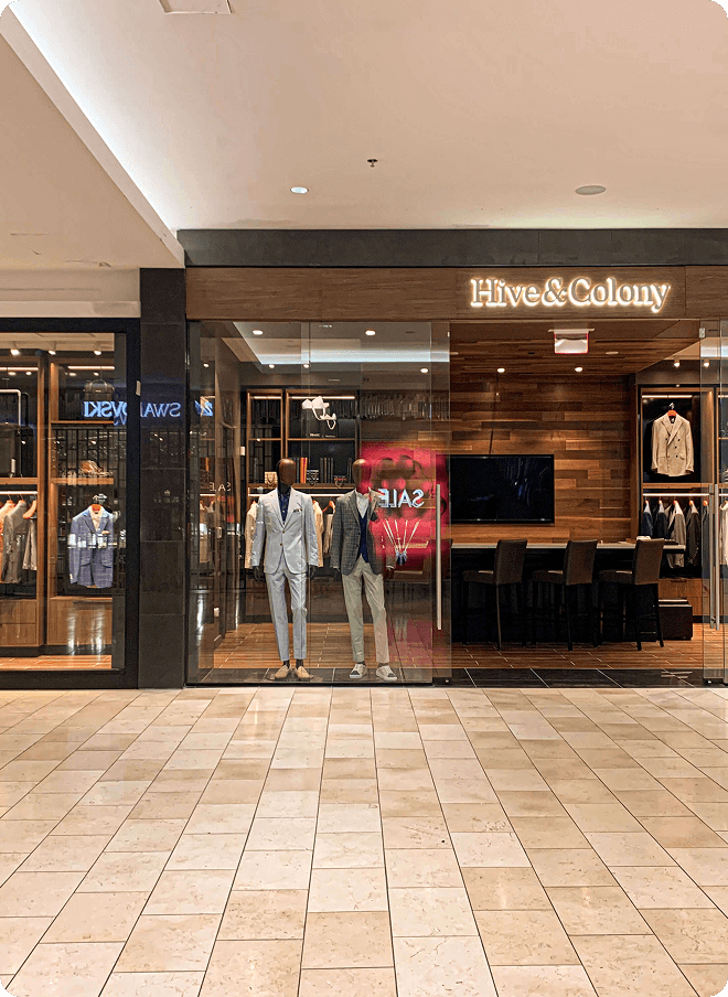 Hive & Colony storefront with mannequins and tailored suits in a mall.
