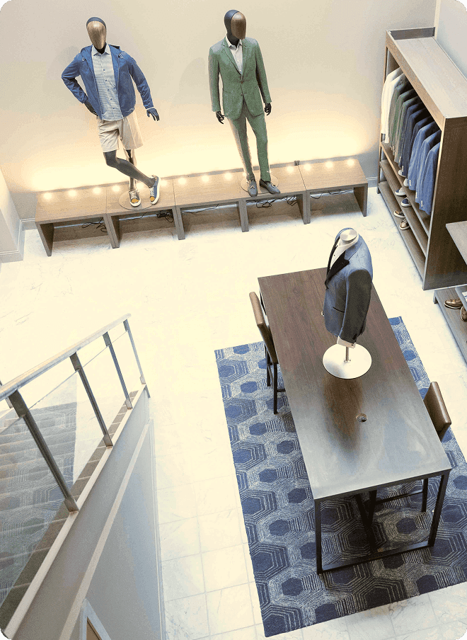 Overhead view of a showroom with mannequins and a central tailoring table.