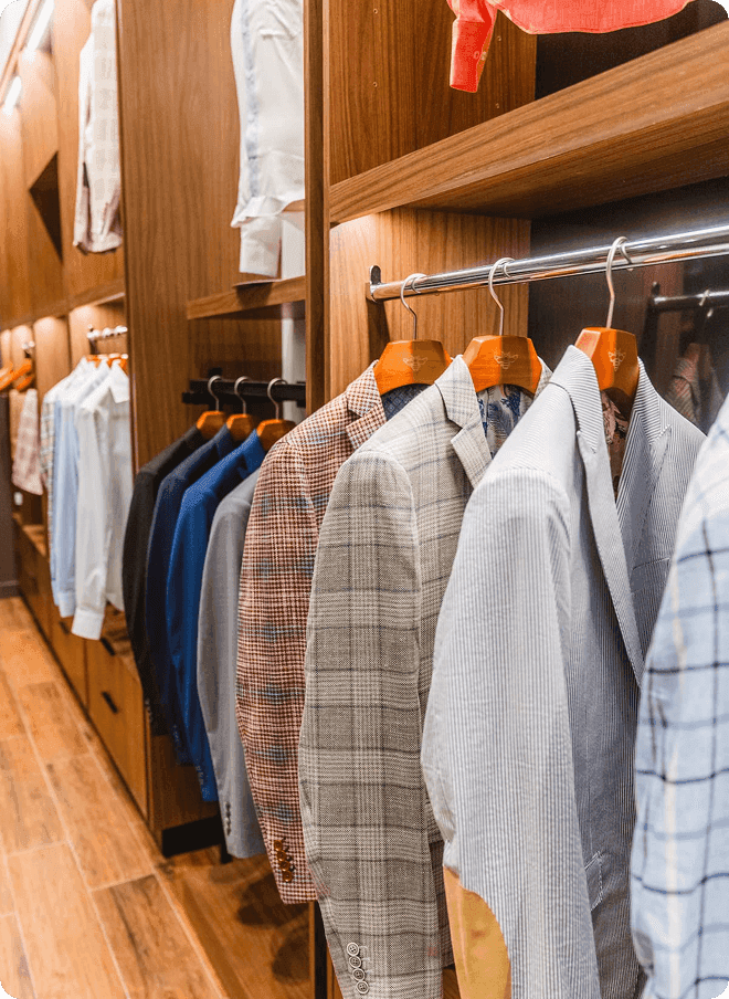 Close-up of plaid jackets and shirts on wooden hangers.
