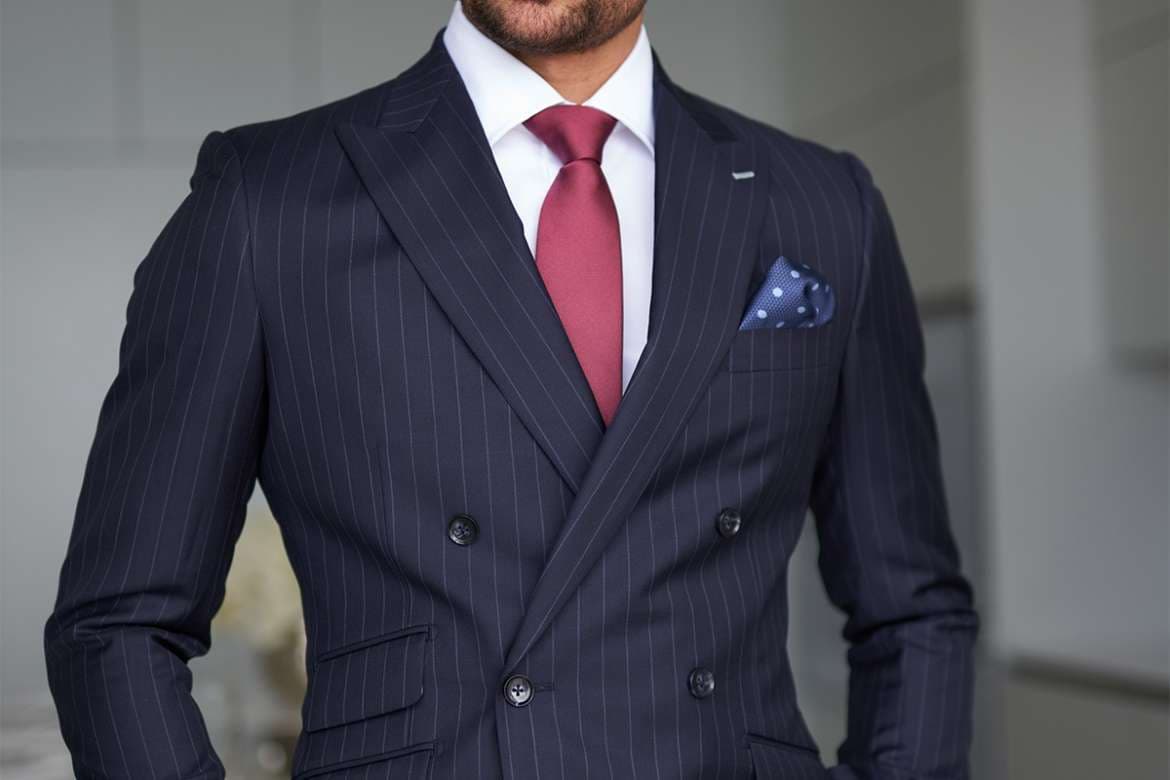 Man wearing a double-breasted pinstripe suit with a red tie.