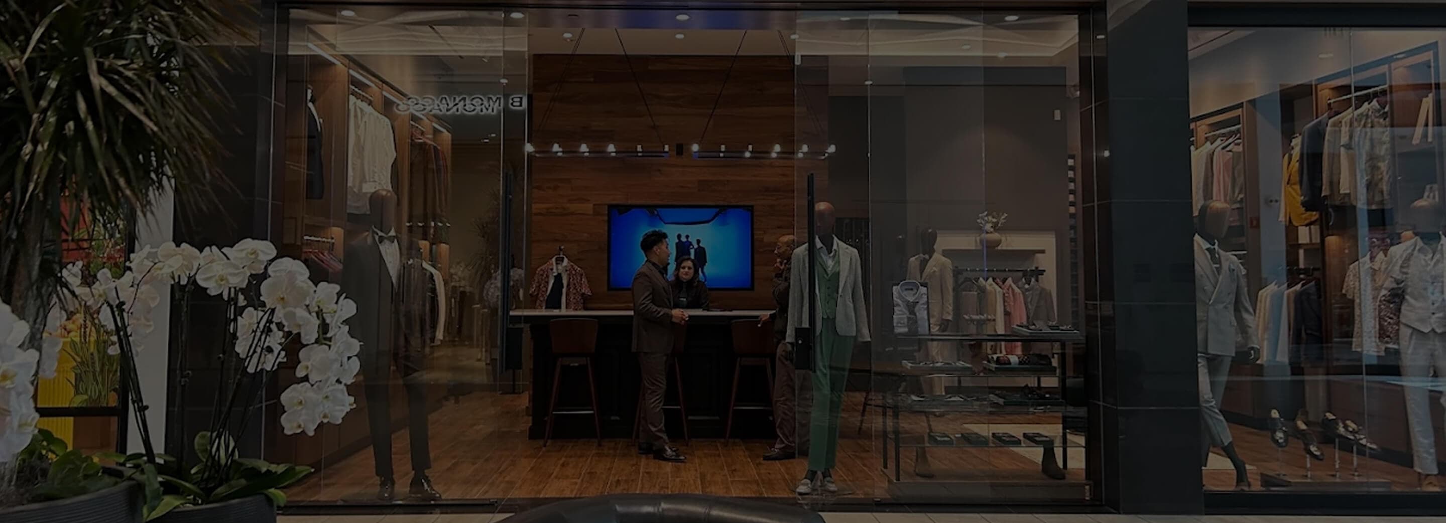 Hive & Colony storefront with orchids, mannequins, and suit displays.