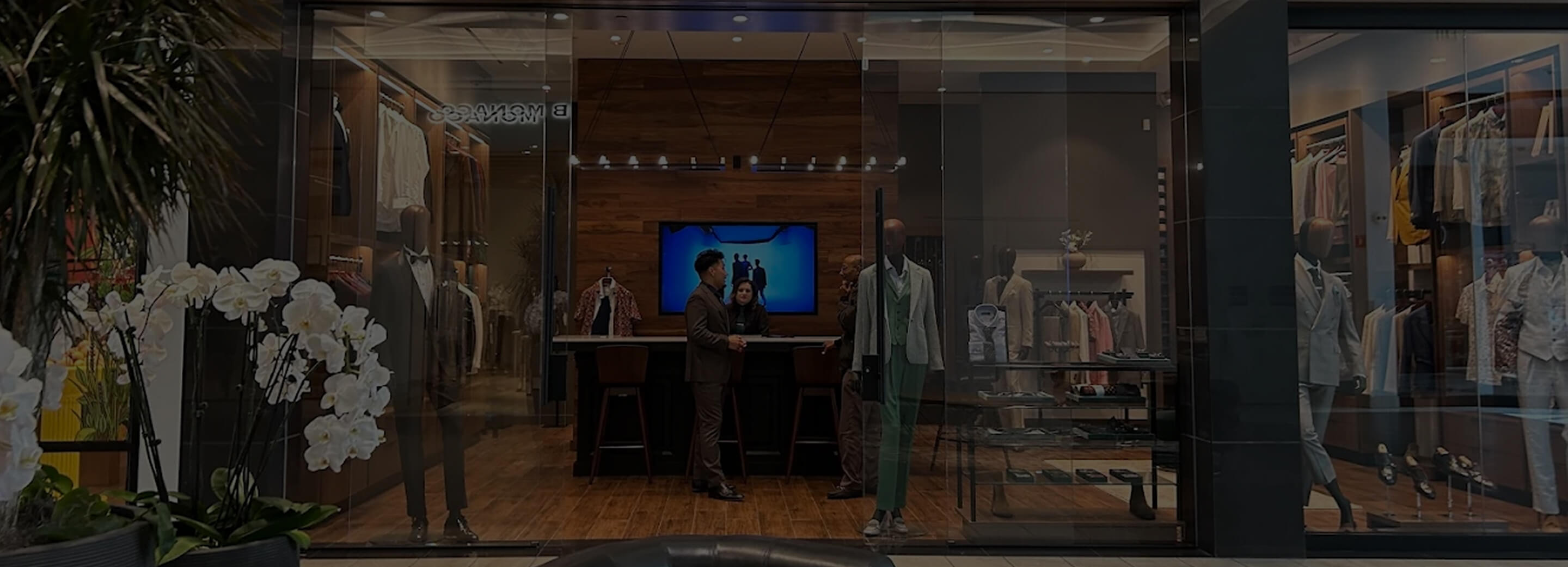 Hive & Colony storefront with orchids, mannequins, and suit displays.
