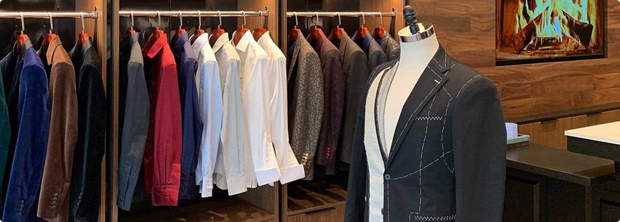 Showroom fitting area with jackets, shirts, and a basted suit form.