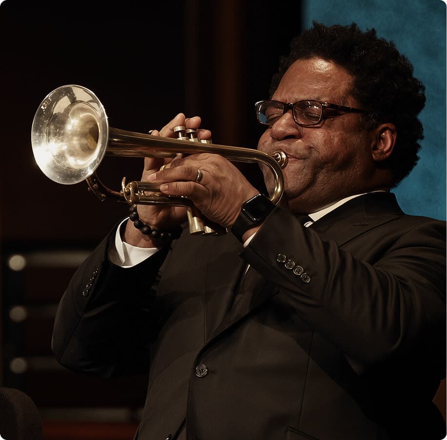 Trumpet player performing on stage in a black suit.