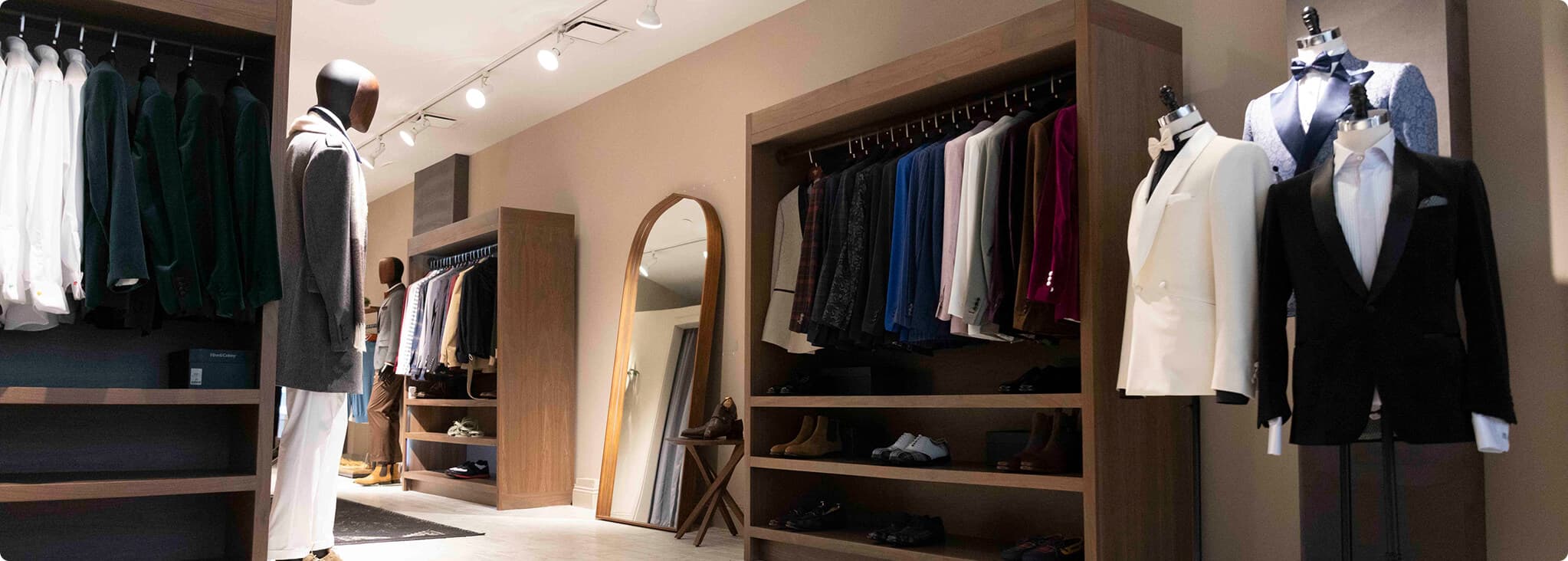 Hive & Colony showroom with hanging suits, mannequins, and dress shoes.