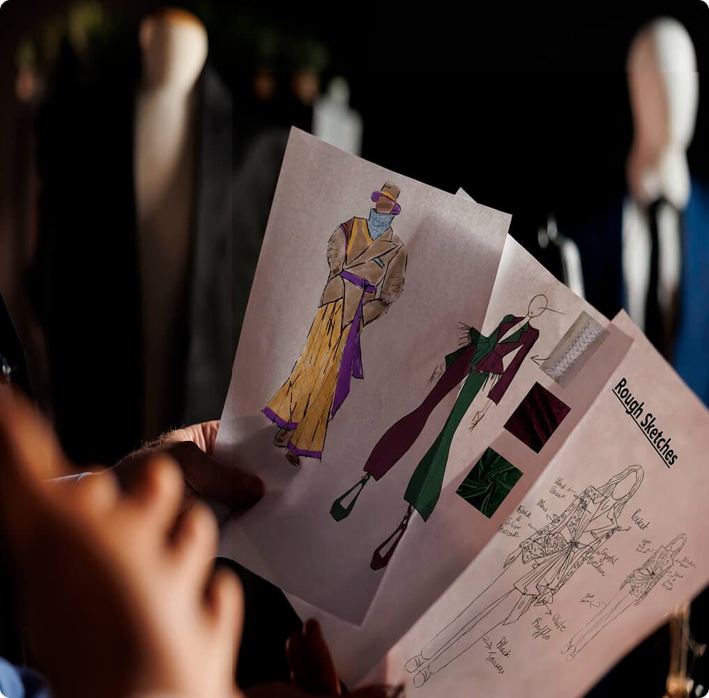 Close-up of colorful fashion sketches held in front of dress forms.