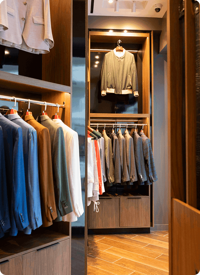 Clothing racks and wood shelving inside a tailored menswear showroom.