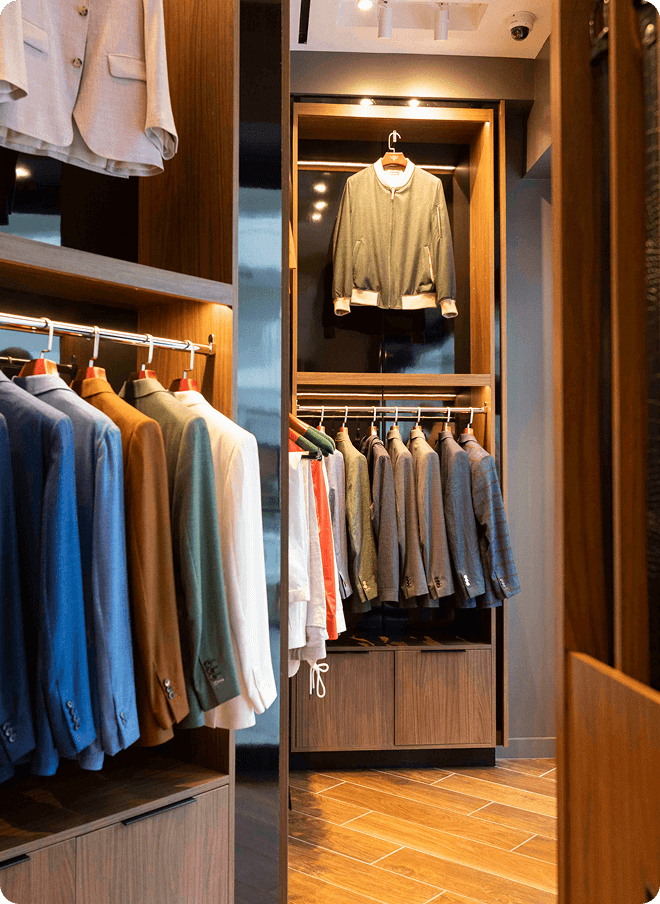 Clothing racks and wood shelving inside a tailored menswear showroom.