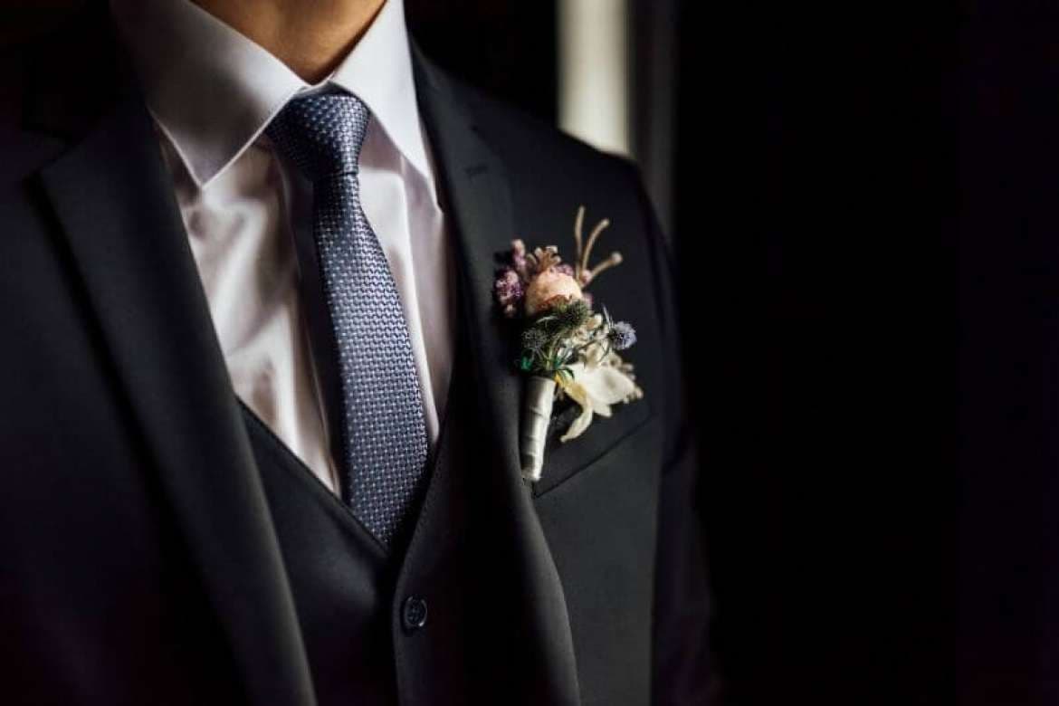 Groom in formal wedding attire outdoors.