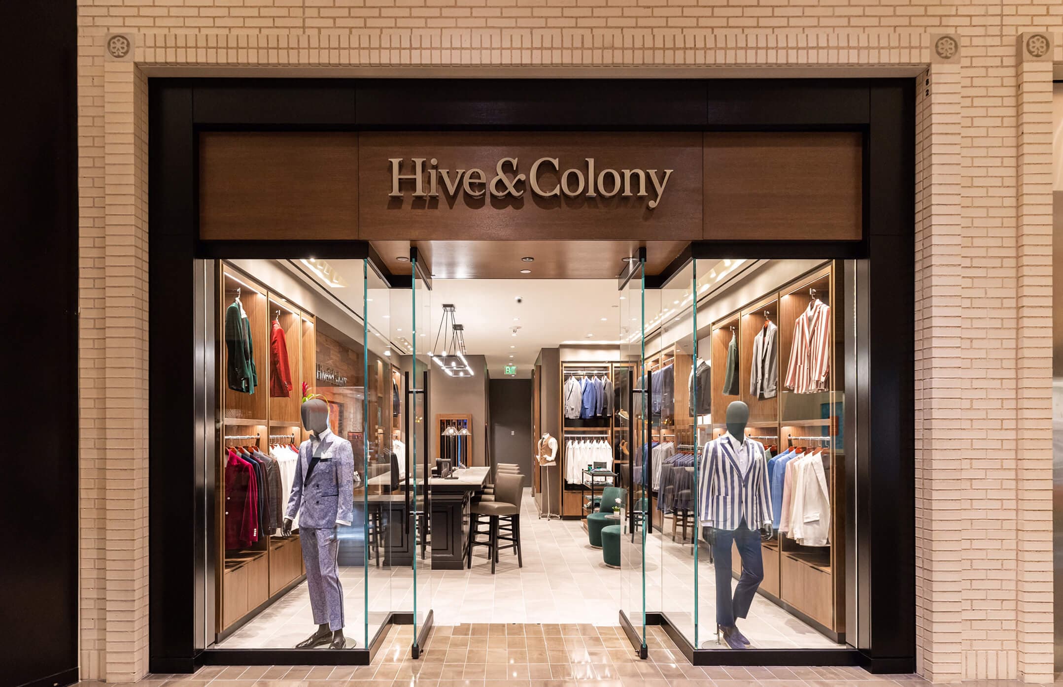 Hive & Colony storefront with mannequins and tailored clothing displays.