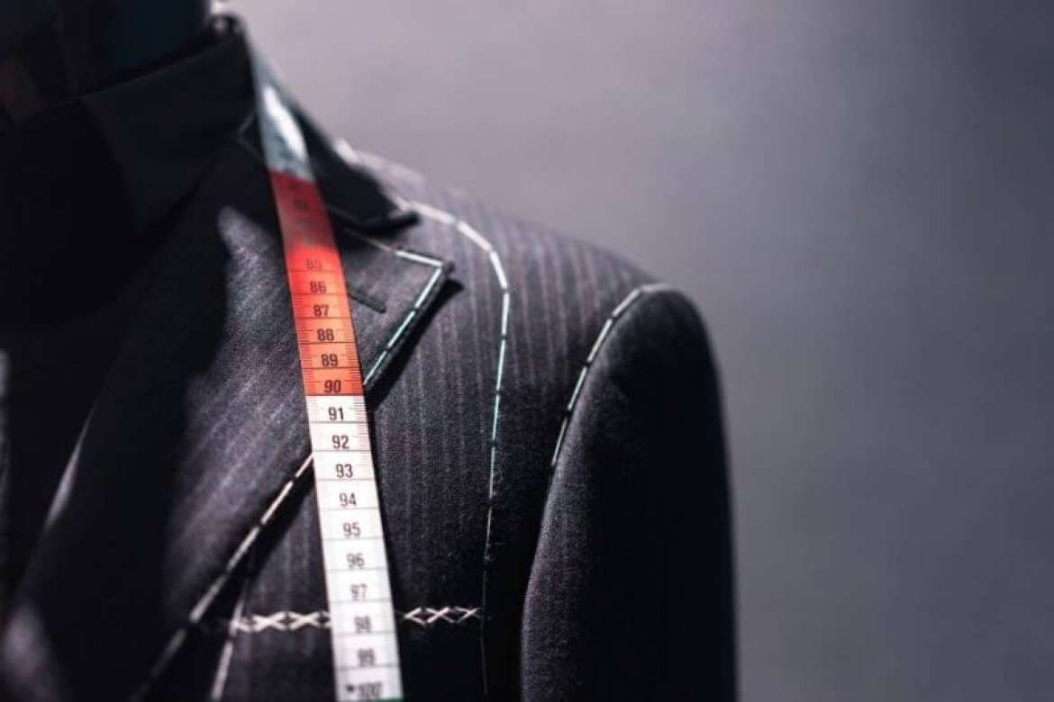 Tailor adjusting a client’s custom suit jacket.
