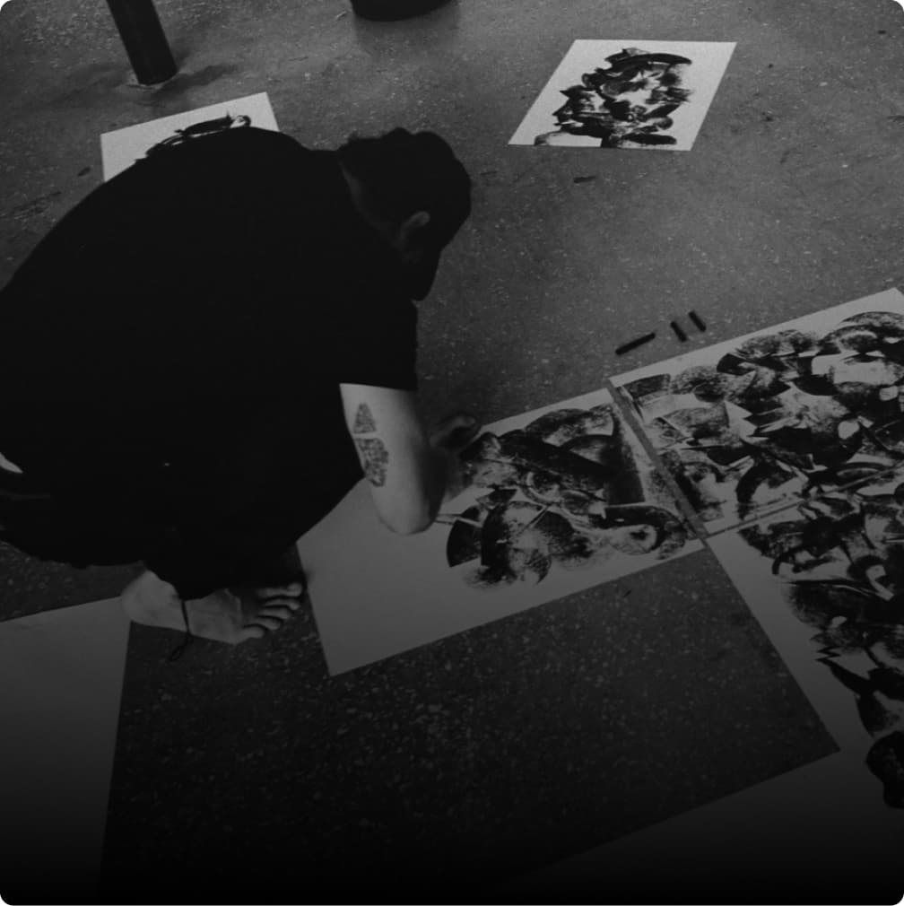 Black-and-white view of an artist working on large printed artwork.