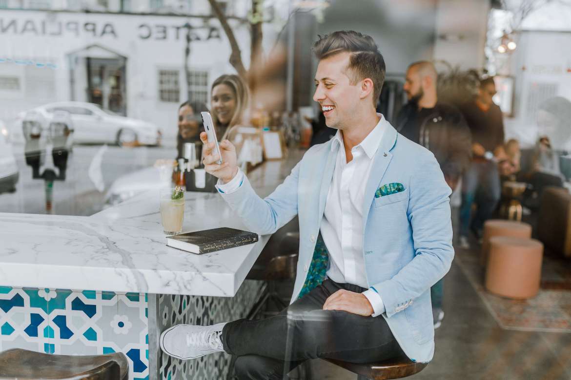 Man in a light blue blazer seated at a café bar.