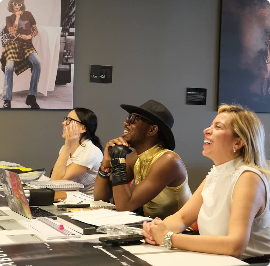 Three judges smiling while reviewing student designs at the A Cut Above competition.