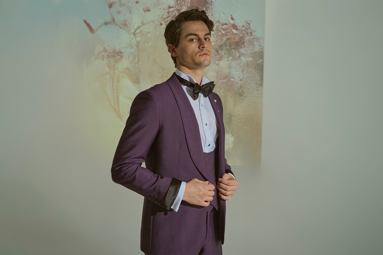 Man in a purple tuxedo adjusting his jacket.