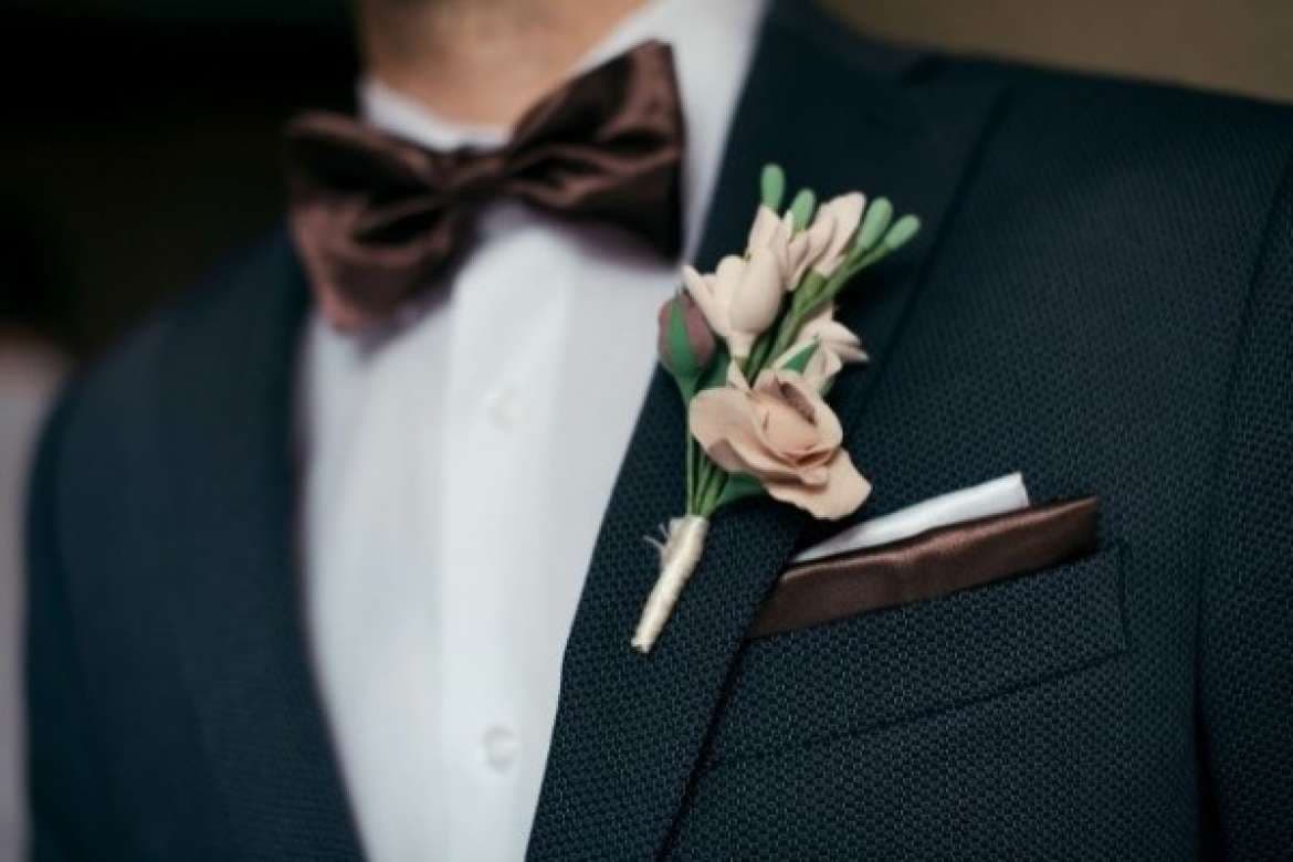 Close-up of a groom’s tuxedo with boutonniere and bow tie.