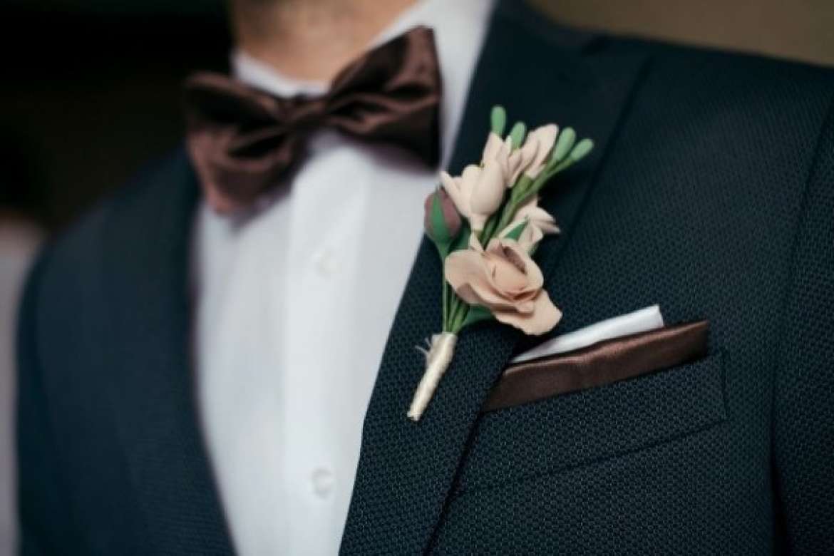 Close-up of a groom’s tuxedo with boutonniere and bow tie.
