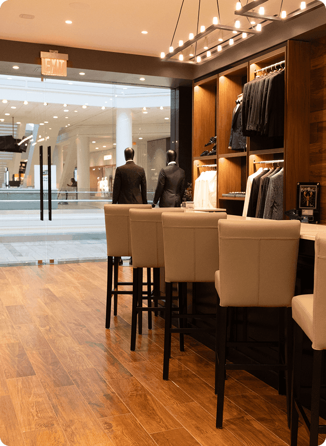 Showroom seating area facing a mall entrance and menswear displays.