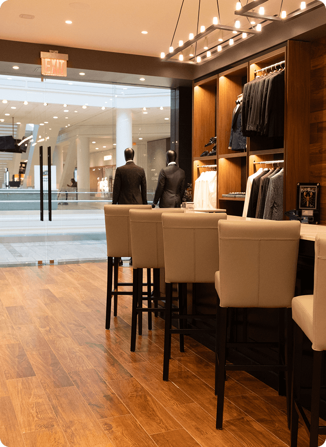 Showroom seating area facing a mall entrance and menswear displays.