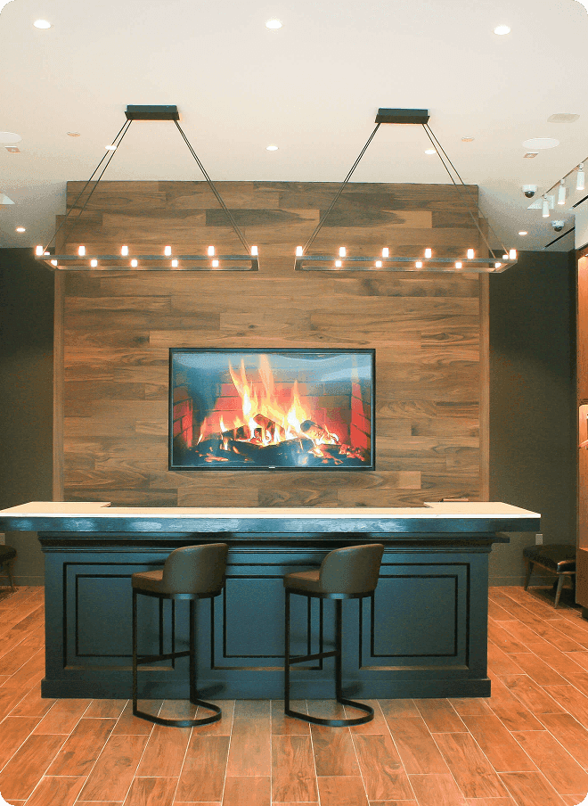 Fitting bar with fireplace screen, pendant lights, and leather stools.