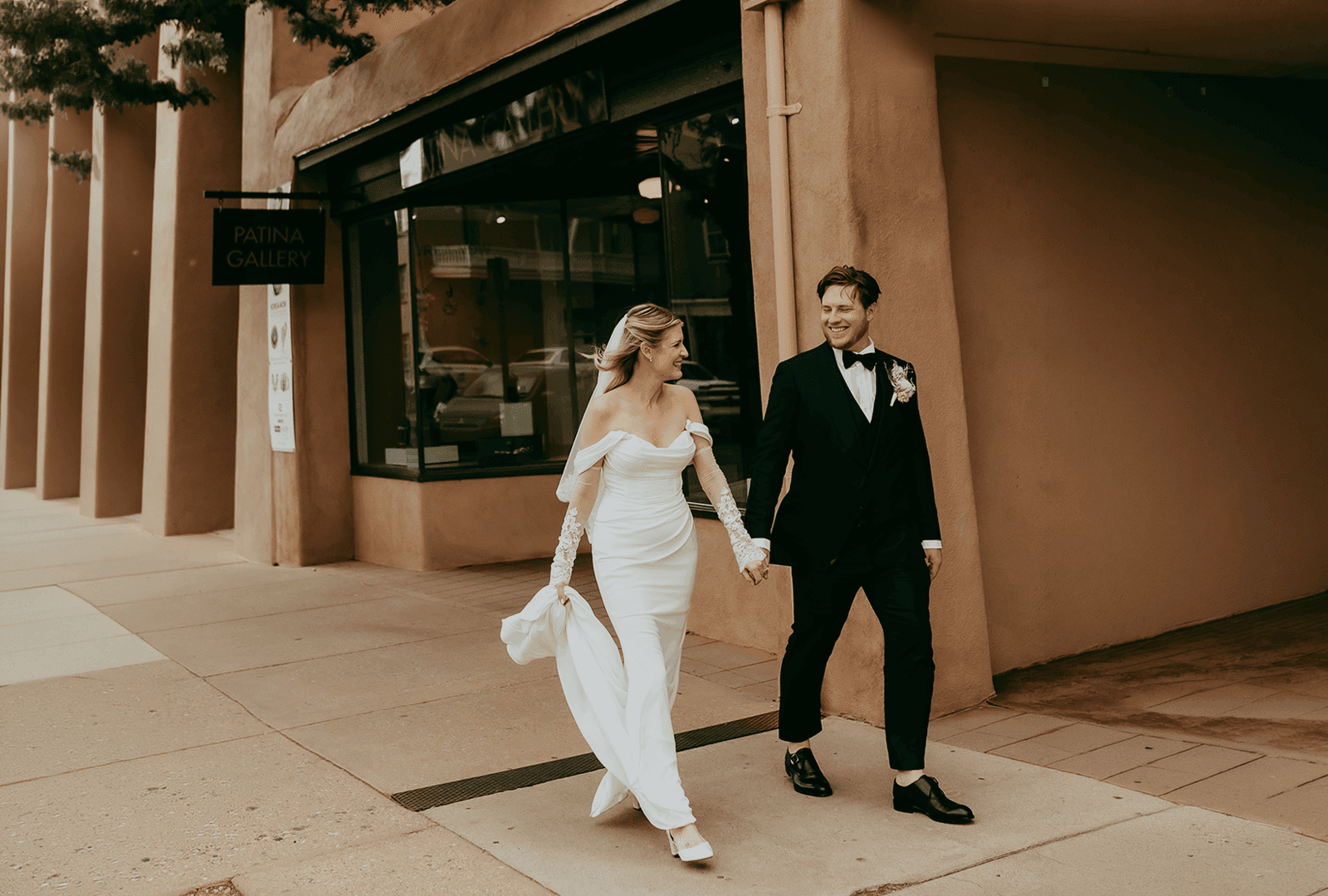 Bride and groom holding hands while walking down a street