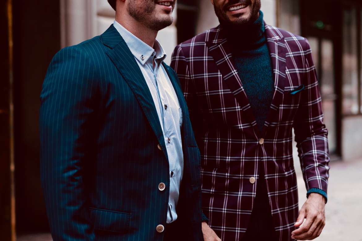 Two men wearing tailored jackets walking together outdoors.
