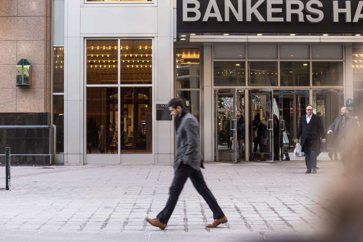 Man in a suit walking outside a Boston storefront.