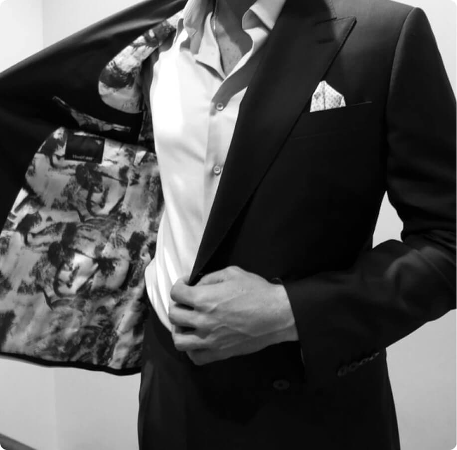 Black-and-white close-up of a man revealing a patterned suit lining.