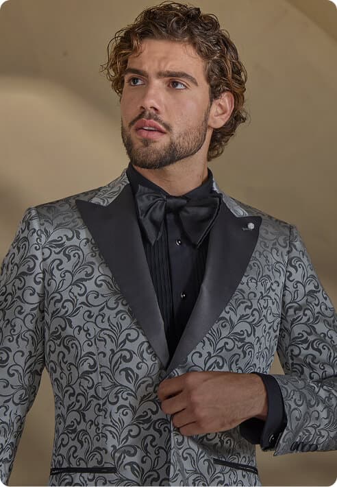 Man in a silver patterned tuxedo with a black bow tie.