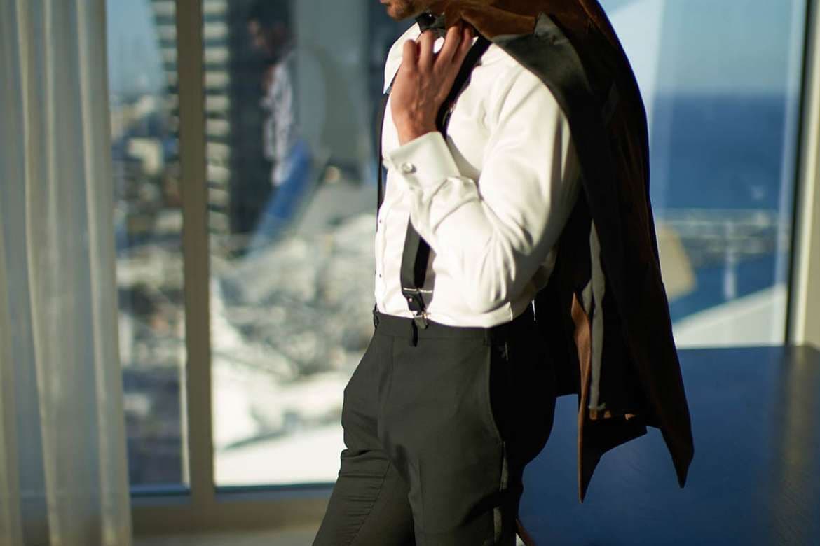 Man wearing suspenders and carrying a jacket over his shoulder.