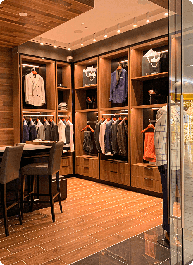 Warm showroom interior with suit jackets, mannequins, and wood displays.