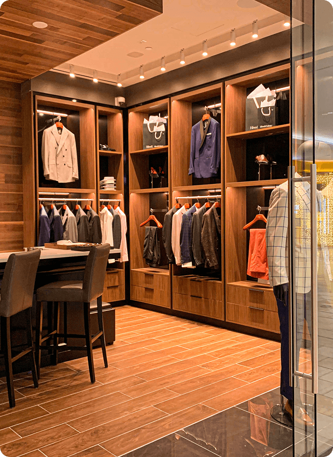 Warm showroom interior with suit jackets, mannequins, and wood displays.