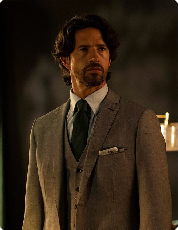 Man in a gray three-piece suit with a green tie.