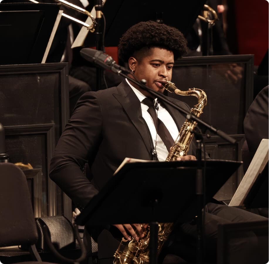 Saxophonist performing on stage in a black suit.