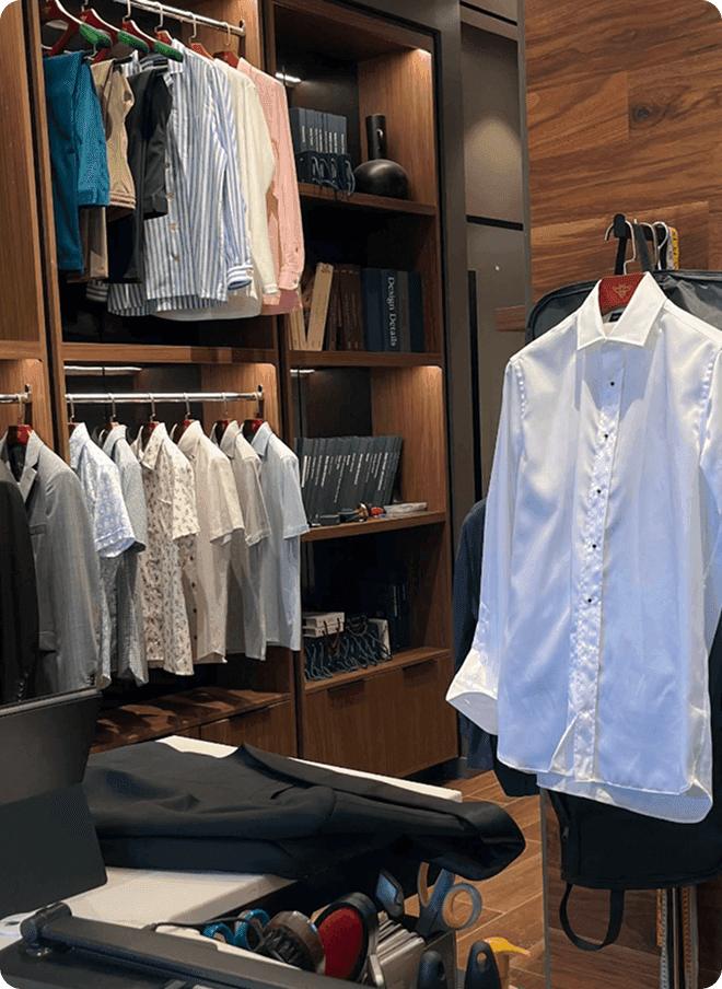 White dress shirt on a tailor form beside wardrobe racks.