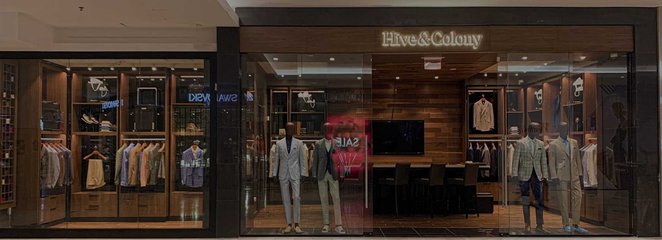 Hive & Colony storefront with mannequins and tailored clothing displays.