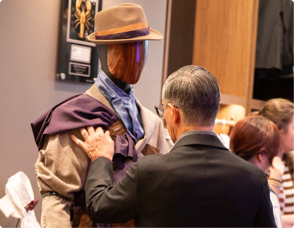 Man adjusting a layered jacket on a mannequin during the A Cut Above showcase.