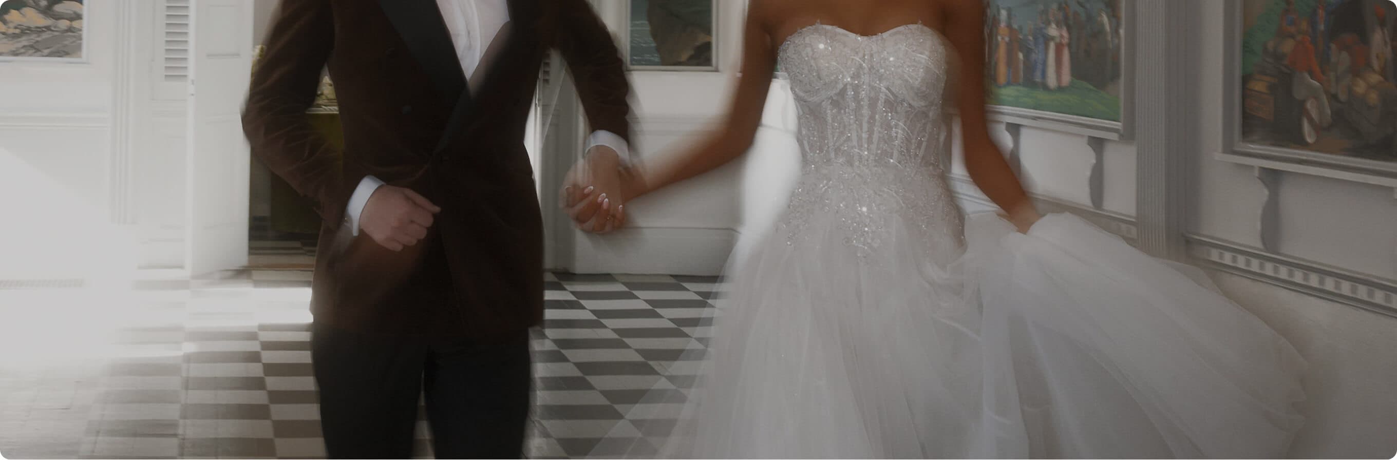 Bride and groom walking hand in hand through an elegant interior.