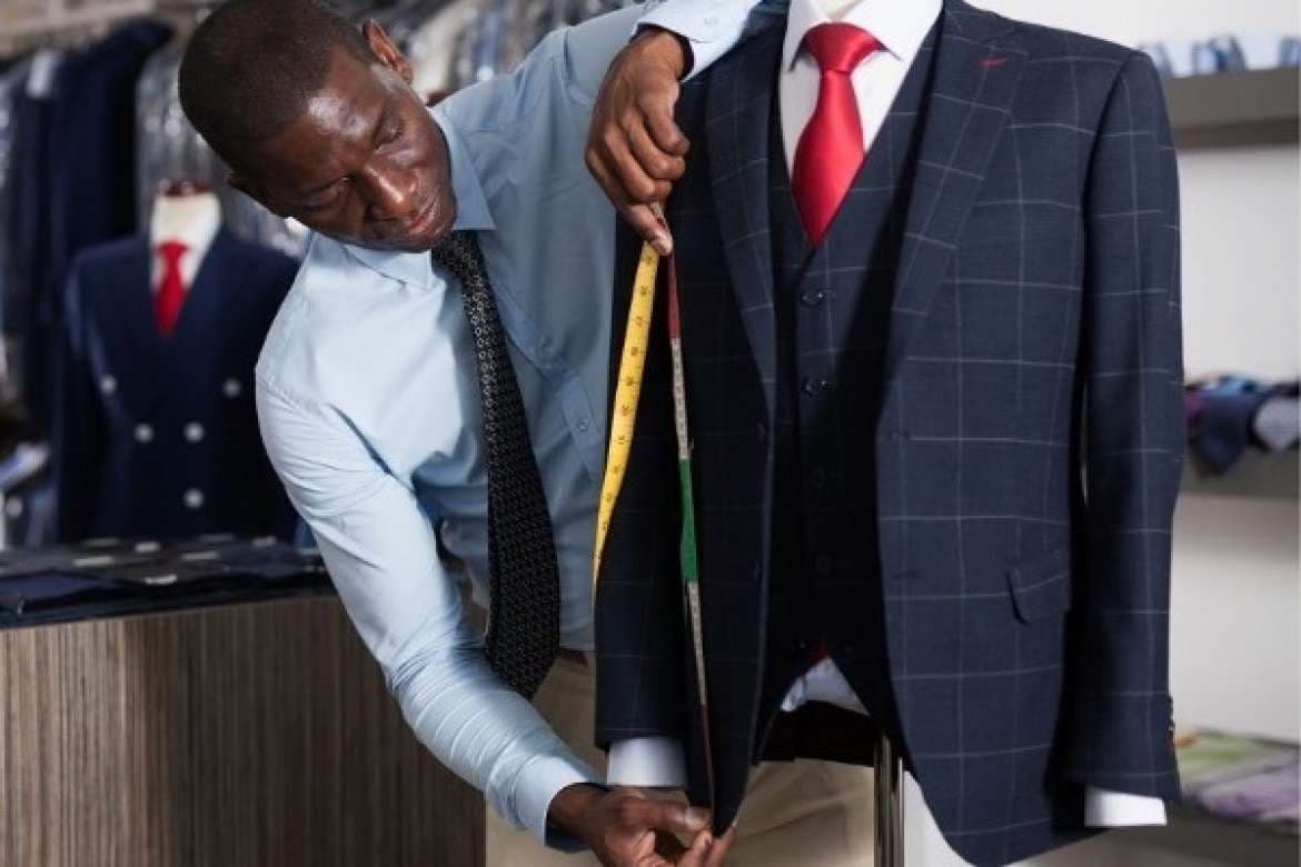 Tailor taking suit measurements on a client.