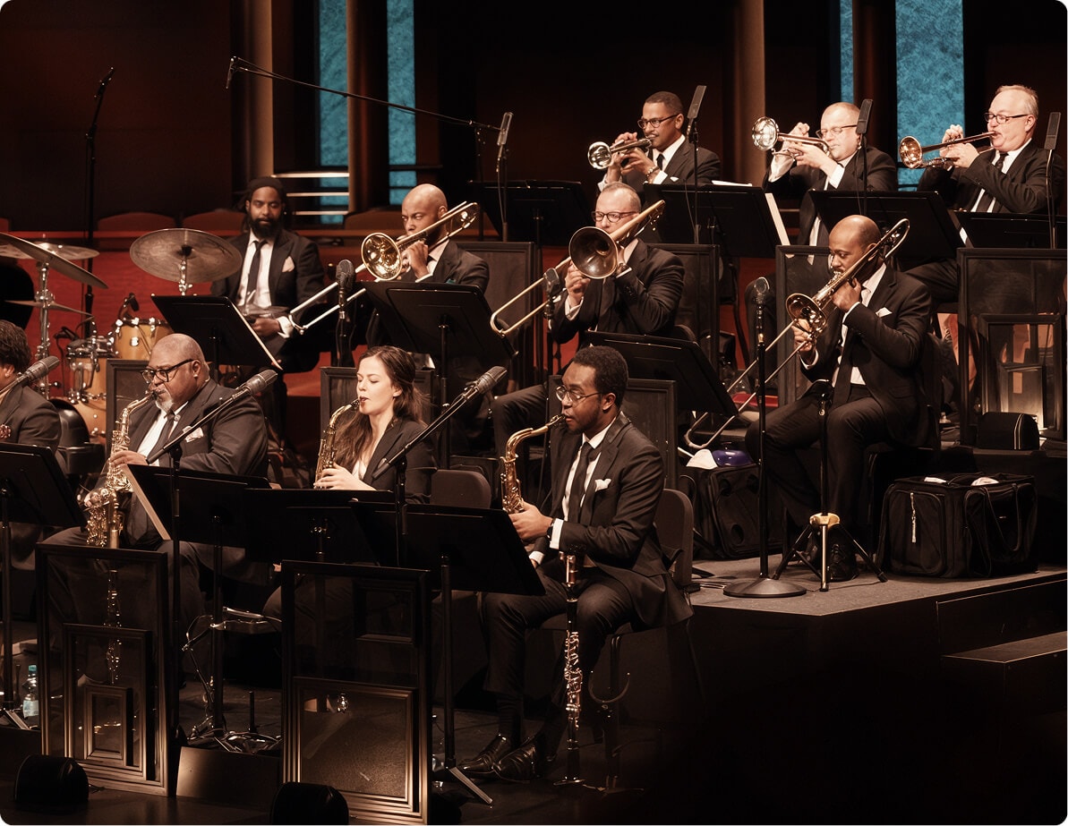 Jazz orchestra performing on stage in formalwear.