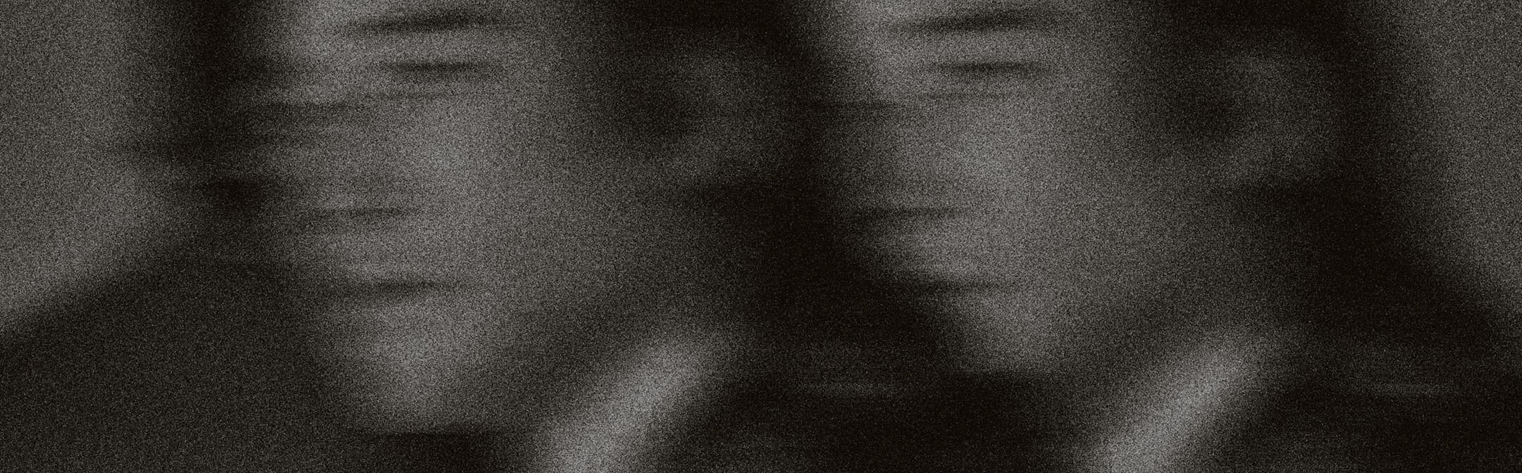 Blurred black-and-white portrait of two figures in suits.